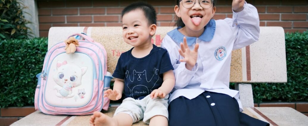 Happy children sitting on a bench making funny faces, creating playful memories.