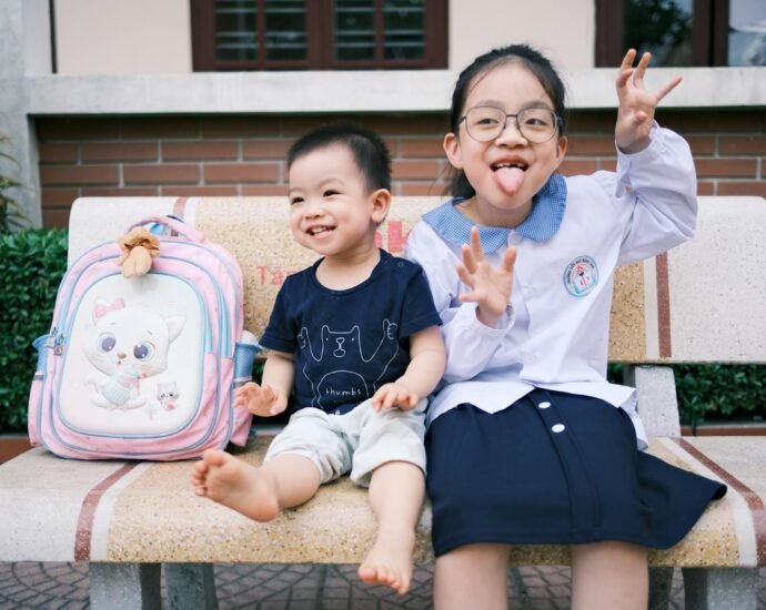 Happy children sitting on a bench making funny faces, creating playful memories.
